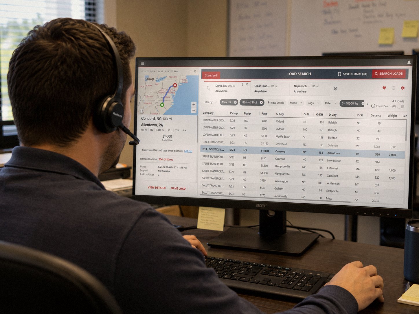 American Tico dispatcher with a headset reviewing the load board